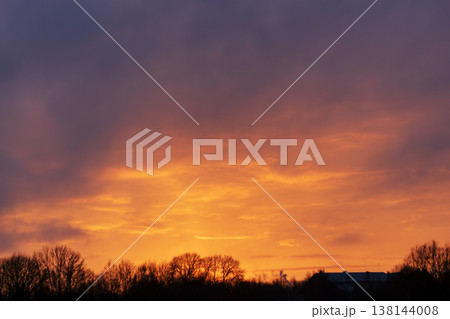 Dramatic sunset sky with orange clouds and dark forest silhouette 138144008