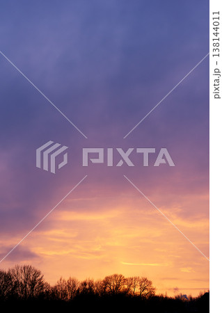 Beautiful sunset sky with purple and orange clouds over dark forest tree line Beautiful sunset sky with purple and orange clouds over dark forest tree line 138144011