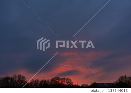 Dramatic dark evening sky with bright red sunset above winter trees Dramatic dark evening sky with bright red sunset above winter trees 138144018