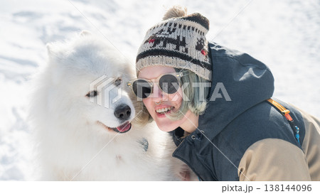 Portrait of a Smiling woman holding fluffy samoyed dog in snowy winter park. Portrait of a Smiling woman holding fluffy samoyed dog in snowy winter park. 138144096