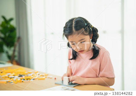 Young Girl Engaged in Creative Play with Building Blocks at Home in Bright Natural Light Young Girl Engaged in Creative Play with Building Blocks at Home in Bright Natural Light 138144282