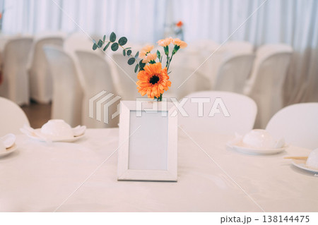 Blank Picture Frame Mockup on Wedding Table with Orange Gerbera Flower Blank Picture Frame Mockup on Wedding Table with Orange Gerbera Flower 138144475