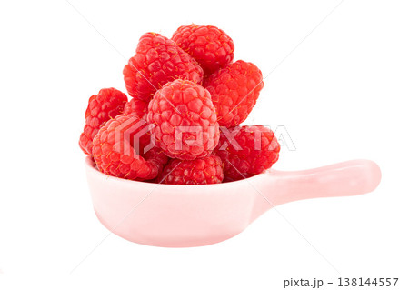 Fresh red raspberries in a small pink ceramic sauce dish with handle on white background isolated with clipping path 138144557