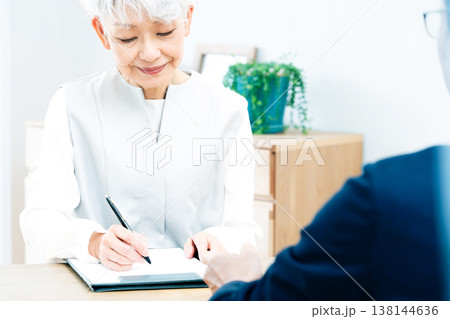 営業マンの説明を聞くシニア女性 138144636