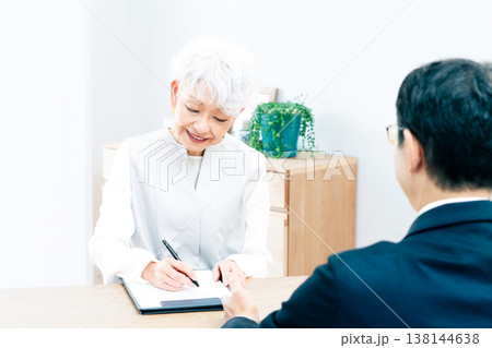 営業マンの説明を聞くシニア女性 138144638