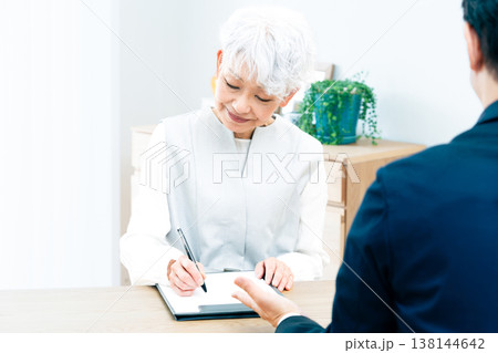 営業マンの説明を聞くシニア女性 138144642