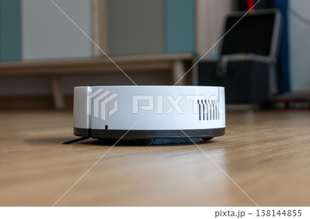 White Robotic Vacuum Cleaner on Modern Wooden Floor - Smart Home Appliance Concept 138144855