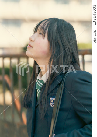 エモい光の中で上を見上げる女子生徒の横顔ポートレート 138145003