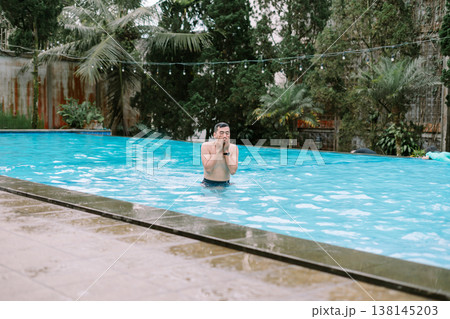 Asian Man Relaxing in Swimming Pool at Hotel Resort Asian Man Relaxing in Swimming Pool at Hotel Resort 138145203