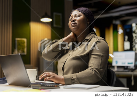 Female assistant in discomfort due to neck stiffness and backache, doing self massage to relieve the pain and strain. Businesswoman struggling with incorrect posture at the office. Female assistant in discomfort due to neck stiffness and backache, doing self massage to relieve the pain and strain. Businesswoman struggling with incorrect posture at the office. 138145328