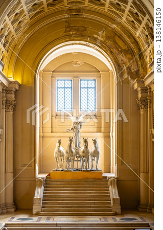 A sculpture of winged victory standing with horses inside the Il Vittoriano monument in Rome. The light filters in from the windows, highlighting the details of the work. A sculpture of winged victory standing with horses inside the Il Vittoriano monument in Rome. The light filters in from the windows, highlighting the details of the work. 138146150