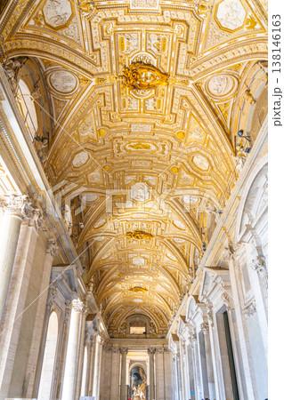 The corridor in Basilica of St Peter shows intricate designs and tall ceilings. Visitors walk through the space, admiring the art and architecture that surrounds them during the day. 138146163