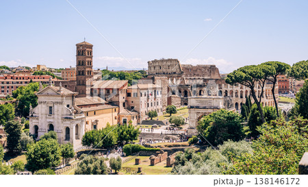 Visitors walk through the Roman Forum with views of the Colosseum in the background. People explore ancient sites under a clear blue sky during the day. Visitors walk through the Roman Forum with views of the Colosseum in the background. People explore ancient sites under a clear blue sky during the day. 138146172