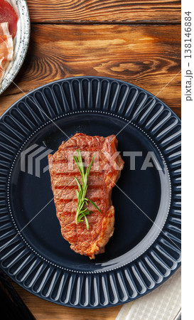 Grilled steak served on a blue plate with herbs at a restaurant table 138146884