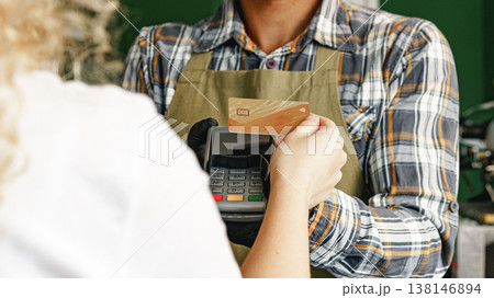 Customer pays with card at a store during a sunny afternoon 138146894