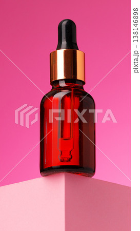 Bottle of serum on a pink background with a simple display setup 138146898