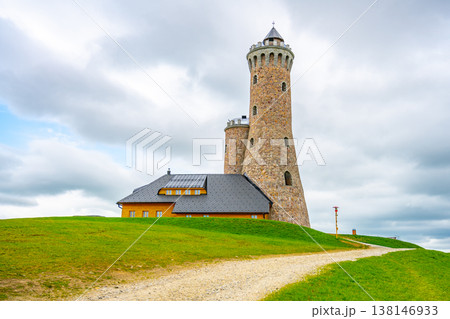 Visitors explore the Dalimil Lookout Tower, a replica located on Vetrov Hill. The tower offers stunning views of the surrounding landscape on a cloudy day. 138146933