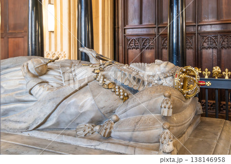 The tomb of Elizabeth I is in Westminster Abbey in London, UK. The stone monument shows the figure of the queen with a crown and regal attire. Visitors observe and reflect on the history. 138146958