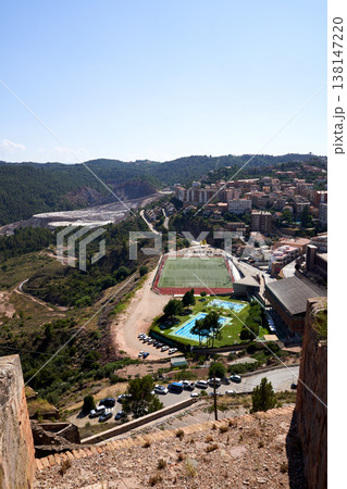 A high-angle view showcasing a picturesque cityscape with a football field, swimming pools, and lush greenery, all under a clear blue sky. A high-angle view showcasing a picturesque cityscape with a football field, swimming pools, and lush greenery, all under a clear blue sky. 138147220