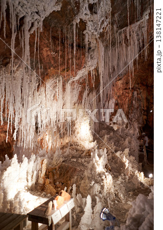 A stunning view inside a salt mine, showcasing natural salt formations with long stalactites hanging down. The textures and lighting create a unique underground landscape. A stunning view inside a salt mine, showcasing natural salt formations with long stalactites hanging down. The textures and lighting create a unique underground landscape. 138147221