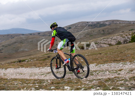 Mountain biker riding on rocky gravel trail Mountain biker riding on rocky gravel trail 138147421