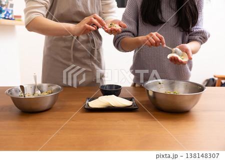 餃子の皮を包む女性と女の子の手元 餃子の皮を包む女性と女の子の手元 138148307