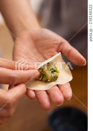 餃子の餡を皮で包む手元のクローズアップ 餃子の餡を皮で包む手元のクローズアップ 138148322