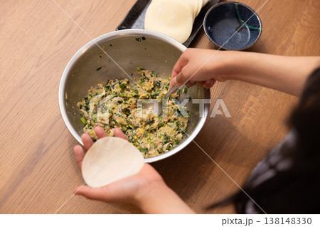 餃子の餡を皮で包む手元のクローズアップ 138148330
