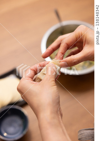 餃子の餡を皮で包む手元のクローズアップ 138148342