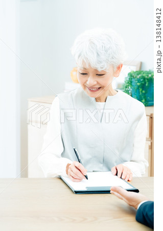 営業マンの説明を聞くシニア女性 営業マンの説明を聞くシニア女性 138148412