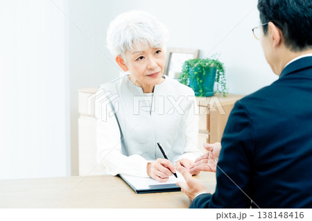 営業マンの説明を聞くシニア女性 営業マンの説明を聞くシニア女性 138148416