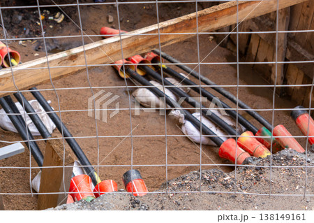 black plastic pipes in ground for drainage of sewage rainwater, lying in trench of sand. 138149161