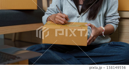 Woman labeling a package for delivery 138149556
