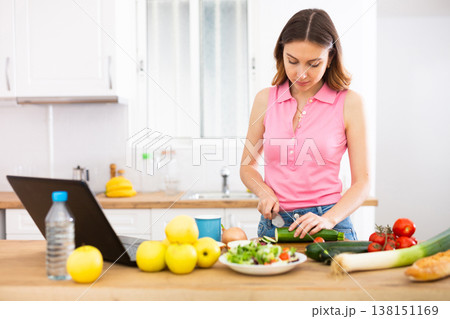 Woman cooking salad recipe from the Internet 138151169