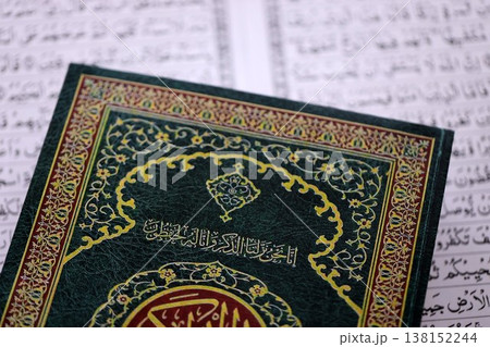 Al Quran Muslim holy book on table in mosque. Details of arabic calligraphy on islamic book cover close up. Concept of Islam religion and praying in arabic countries 138152244