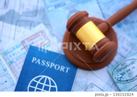 Judgement gavel on passport pages full of colorful stamps after travel and tourism. Border control and lawsuit concept. Immigration and travel around the world 138152824