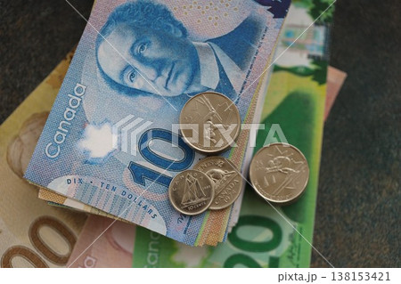 Canadian dollar money bills and cent coins pile on table. Canada coins on banknotes of CAD currency close up. Concept of business, taxes and banking in Canada Canadian dollar money bills and cent coins pile on table. Canada coins on banknotes of CAD currency close up. Concept of business, taxes and banking in Canada 138153421