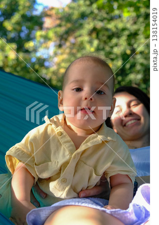Baby in Yellow Shirt with Mother Outdoors 138154019