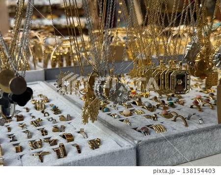 Gold jewelry display with necklaces, rings and various pendants at a market stall, selective focus Gold jewelry display with necklaces, rings and various pendants at a market stall, selective focus 138154403
