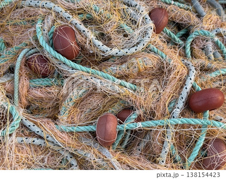Fishing nets with colorful ropes and buoys, arranged in a textured pattern, suitable as background 138154423
