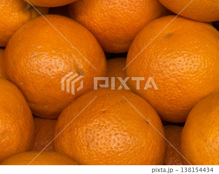 Oranges stacked together forming a textured background of fresh and vibrant citrus fruits Oranges stacked together forming a textured background of fresh and vibrant citrus fruits 138154434