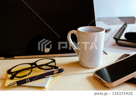 Home office desk with laptop, notebook, pen, glasses and mug arranged for remote work, study or freelance business Home office desk with laptop, notebook, pen, glasses and mug arranged for remote work, study or freelance business 138155420