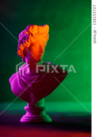 Classical sculpture bust illuminated with vibrant neon purple orange and green gradient lighting Classical sculpture bust illuminated with vibrant neon purple orange and green gradient lighting 138155727