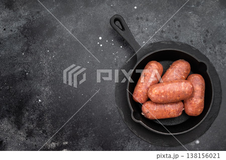 Raw butcher style pork sausages in cast iron pan on dark background, fresh uncooked sausage links ready for grilling or frying.. 138156021