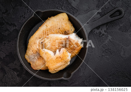 Pan fried tilapia fillet pieces served in cast iron skillet on isolated background with copy space, healthy white fish seafood meal. Pan fried tilapia fillet pieces served in cast iron skillet on isolated background with copy space, healthy white fish seafood meal. 138156025