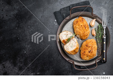Chicken Kyiv breaded chicken cutlet stuffed chicken with butter filling served in skillet with garlic and thyme on dark background 138156043