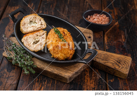 Chicken Kiev traditional breaded chicken cutlet stuffed chicken with butter filling served in cast iron skillet with thyme Chicken Kiev traditional breaded chicken cutlet stuffed chicken with butter filling served in cast iron skillet with thyme 138156045