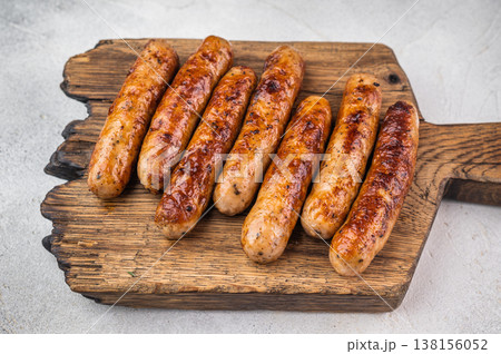Pan fried sausages arranged on wooden board with herbs and spices. Browned pork meat links on light background perfect for barbecue meal. Pan fried sausages arranged on wooden board with herbs and spices. Browned pork meat links on light background perfect for barbecue meal. 138156052