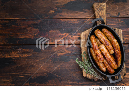 Grilled sausages in cast iron pan with thyme on rustic wooden table. Juicy browned pork meat links ready for dinner or barbecue with copy space. Grilled sausages in cast iron pan with thyme on rustic wooden table. Juicy browned pork meat links ready for dinner or barbecue with copy space. 138156053