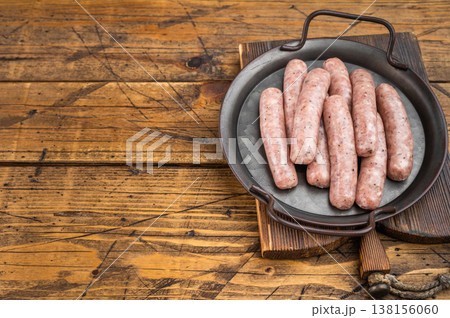 Raw pork sausages in pan on wooden background, fresh minced meat sausage links ready for frying or grilling. Raw pork sausages in pan on wooden background, fresh minced meat sausage links ready for frying or grilling. 138156060